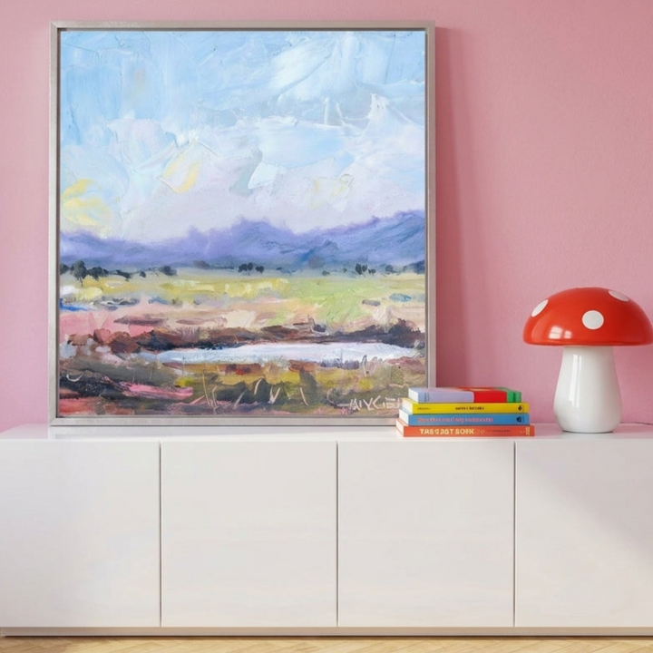 Canvas wall art with a silver leaf surround standing on a sideboard in a colourful eclectic bedroom