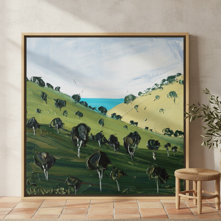 Oversized statement canvas wall art with a natural timber surround leaning against the wall in a Mediterranean home office