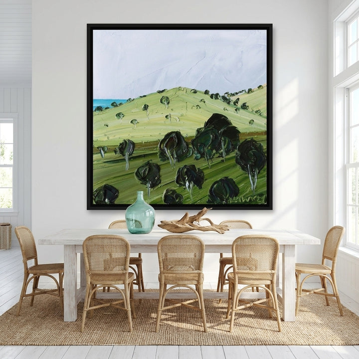 Oversized statement canvas wall art with a black surround styled on the wall in a coastal dining room