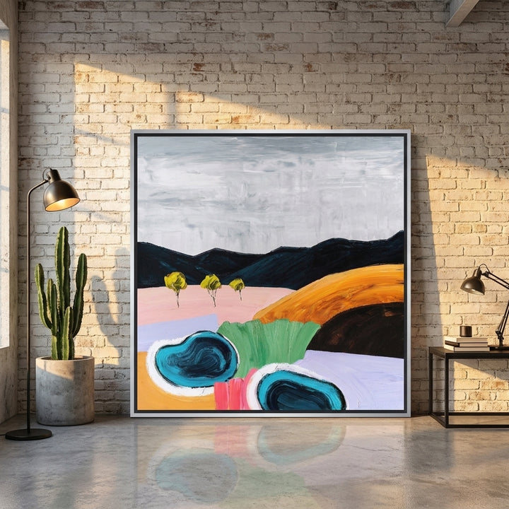 Oversized statement canvas wall art with a silver leaf surround leaning against the wall in an industrial loft living room
