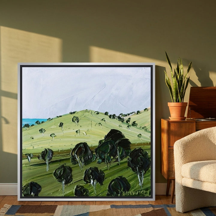 Canvas wall art with a silver leaf surround leaning against the wall in a mid-century living room