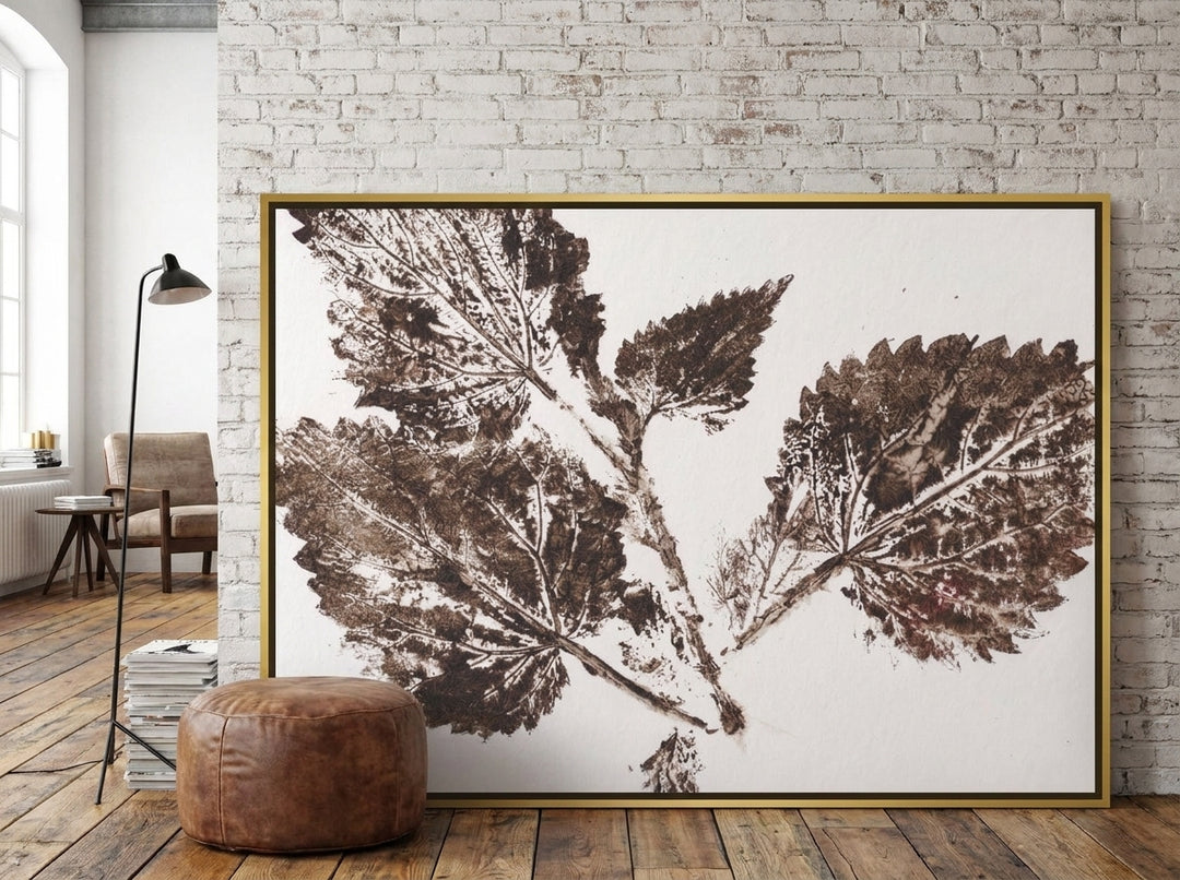 Oversized statement canvas wall art with a gold leaf surround leaning against the wall in an industrial loft living room