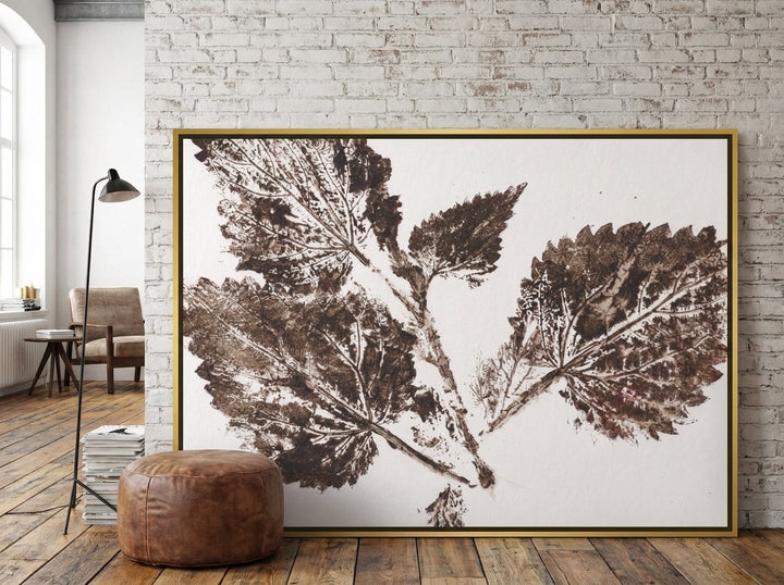 Oversized statement canvas wall art with a gold leaf surround leaning against the wall in an industrial loft living room