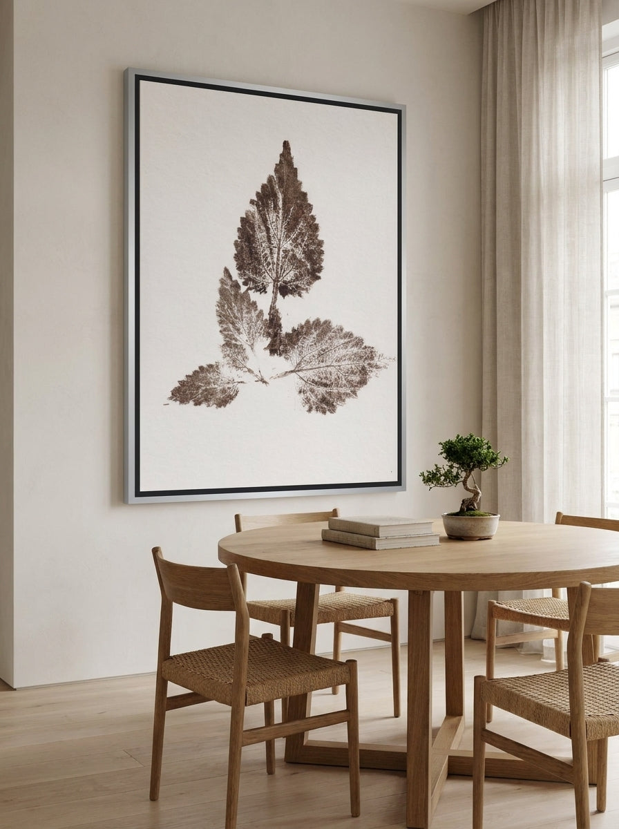 Oversized statement canvas wall art with a silver leaf surround styled on the wall in a warm Japandi dining room