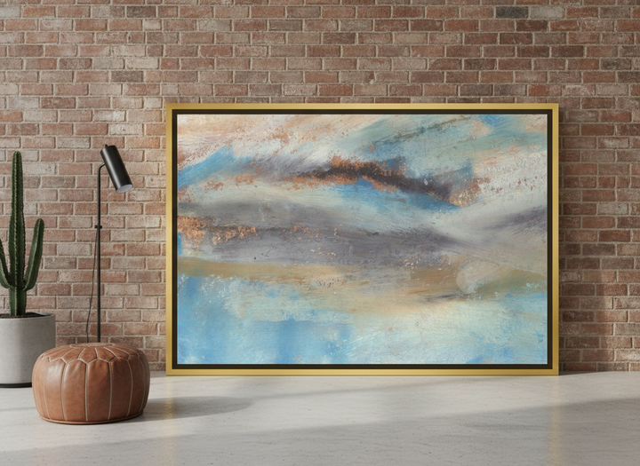 Oversized statement canvas wall art with a gold leaf surround leaning against the wall in an industrial loft living room