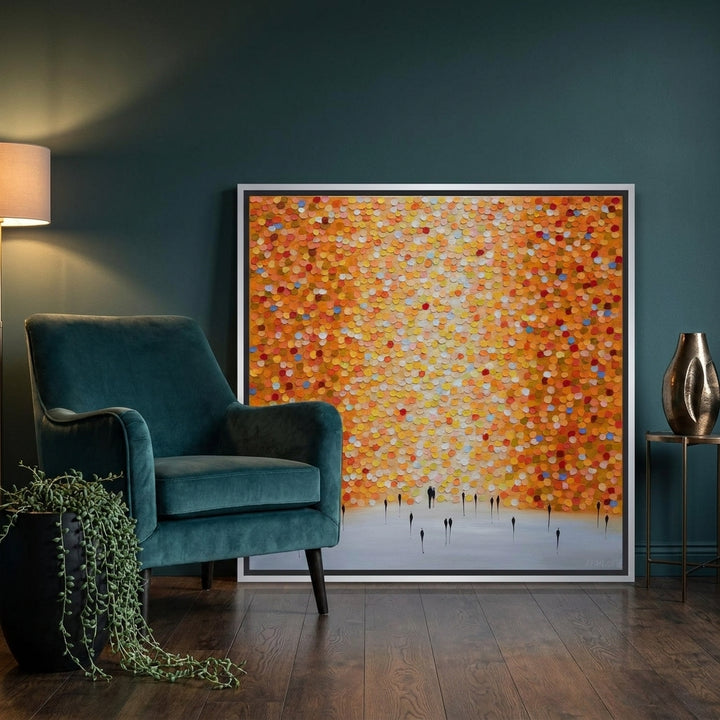 Canvas wall art with a silver leaf surround leaning against the wall in a moody living room