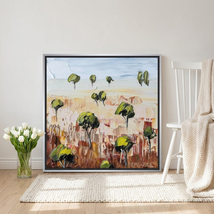 Canvas wall art with a silver leaf surround leaning against the wall in a bright Scandinavian home office
