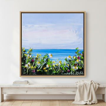 Canvas wall art with a natural timber surround standing on a console in a coastal bedroom