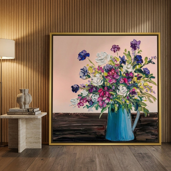 Oversized statement canvas wall art with a gold leaf surround leaning against the wall in a luxe living room