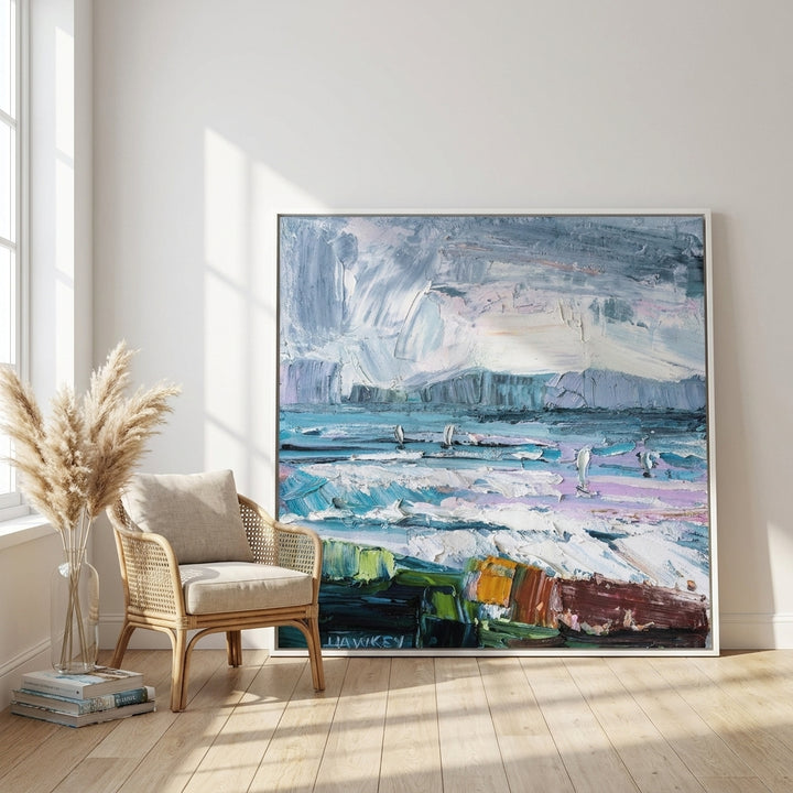 Oversized statement canvas wall art with a white surround leaning against the wall in a coastal dining room