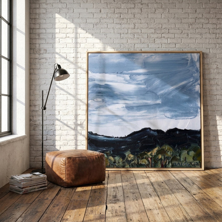 Oversized statement canvas wall art with a natural timber surround leaning against the wall in an industrial loft home office