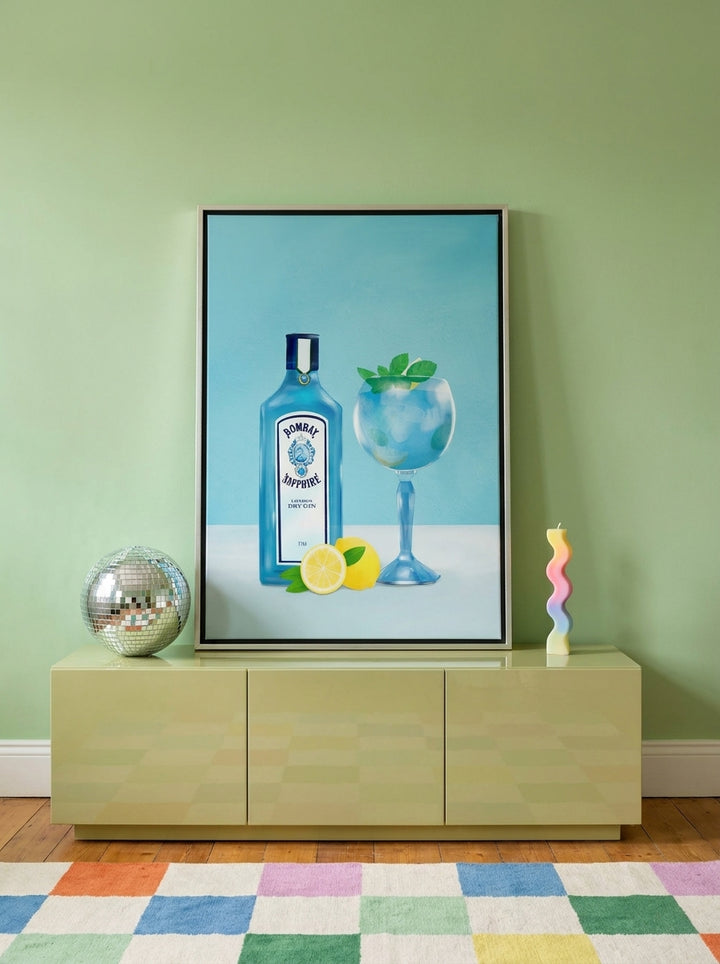 Canvas wall art with a silver leaf surround standing on a sideboard in a colourful eclectic bedroom