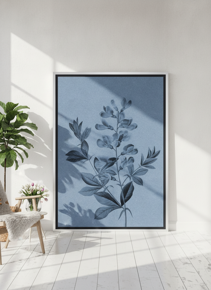 Oversized statement canvas wall art with a silver leaf surround leaning against the wall in a bright Scandinavian living room