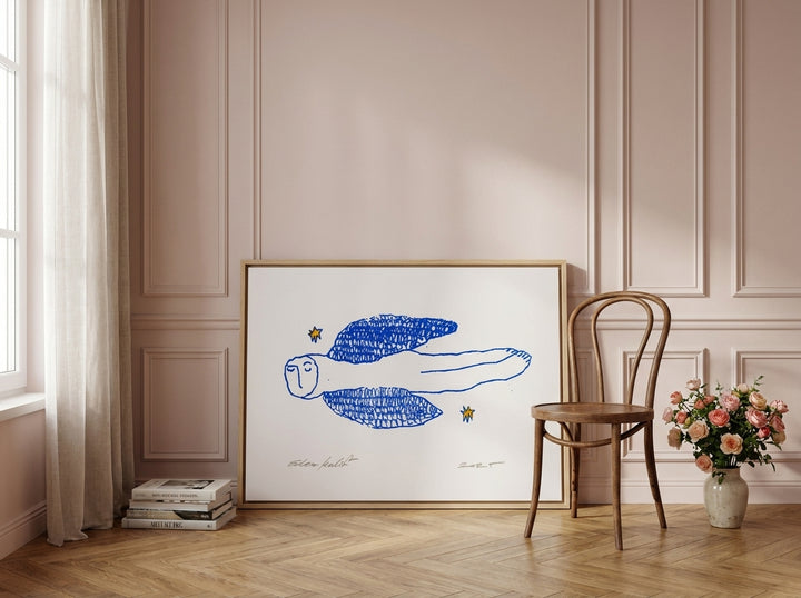 Oversized statement canvas wall art with a natural timber surround leaning against the wall in a Parisian living room