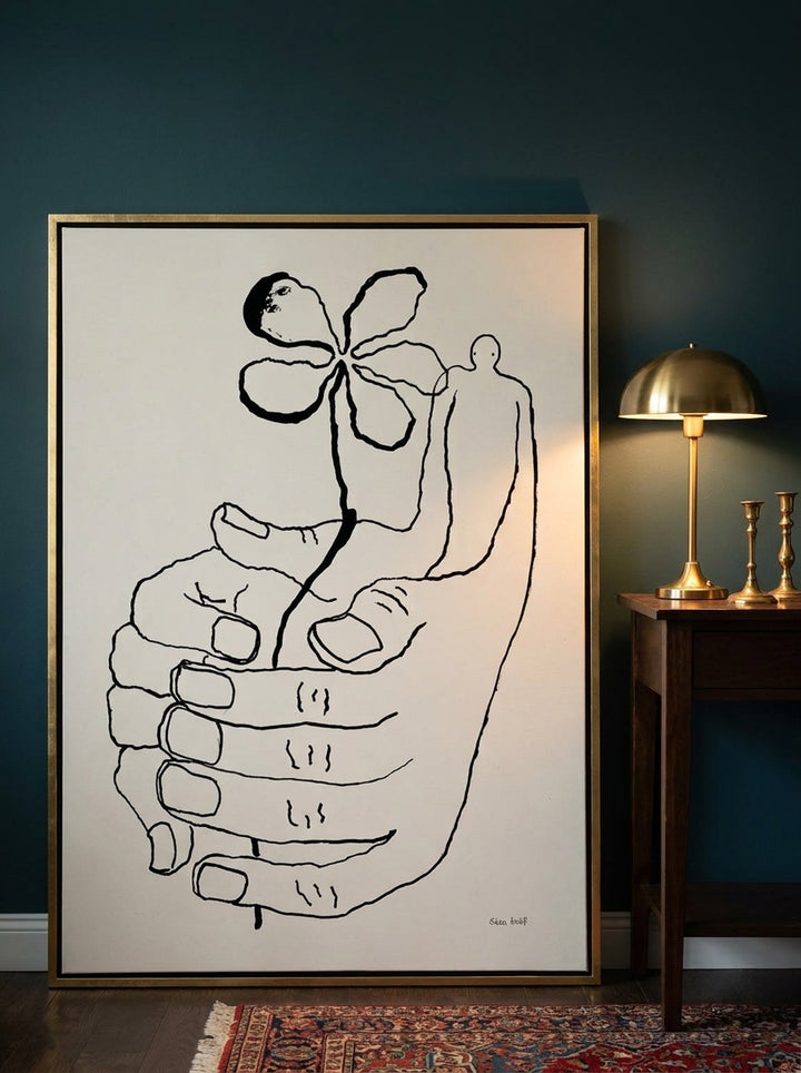 Oversized statement canvas wall art with a gold leaf surround leaning against the wall in a moody home office