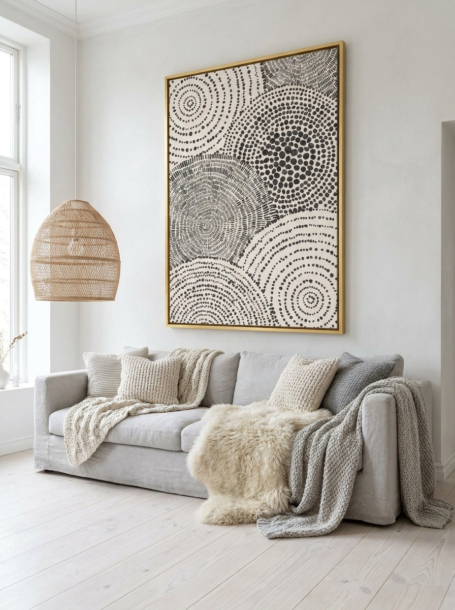 Oversized statement canvas wall art with a gold leaf surround styled on the wall in a bright Scandinavian living room