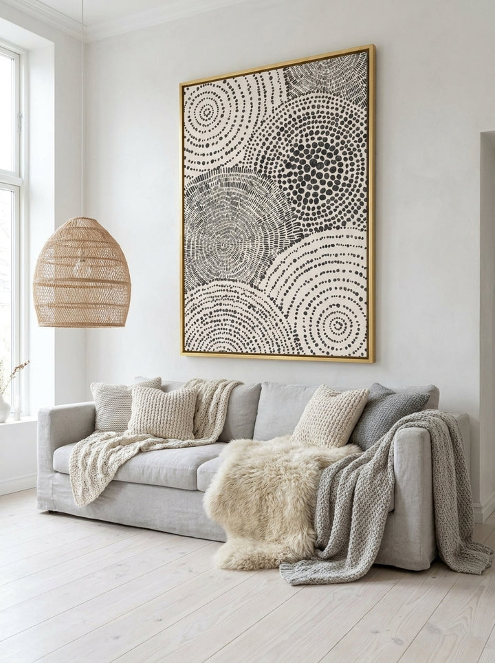 Oversized statement canvas wall art with a gold leaf surround styled on the wall in a bright Scandinavian living room