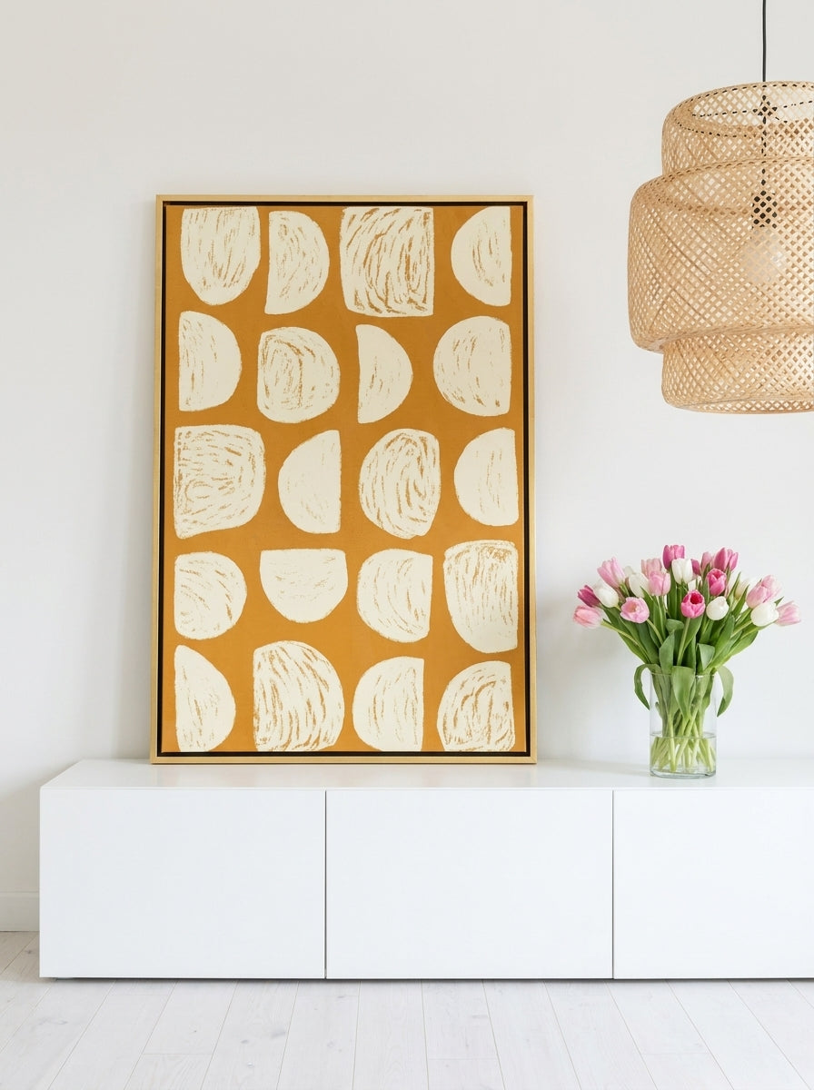 Canvas wall art with a gold leaf surround standing on a sideboard in a bright Scandinavian living room