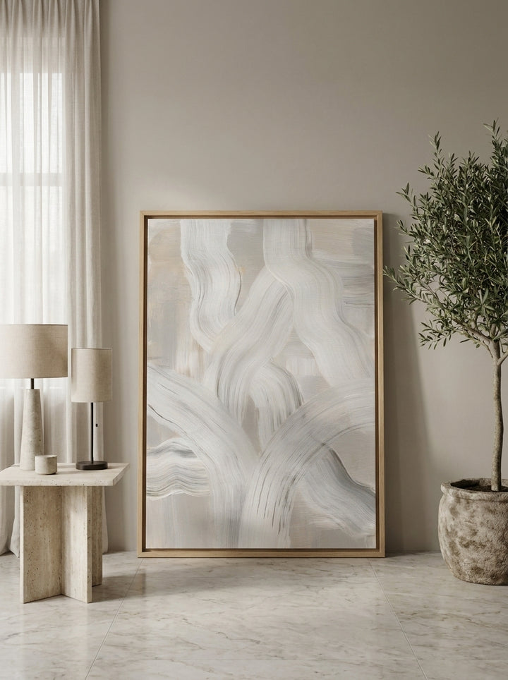 Oversized statement canvas wall art with a natural timber surround leaning against the wall in a luxe living room