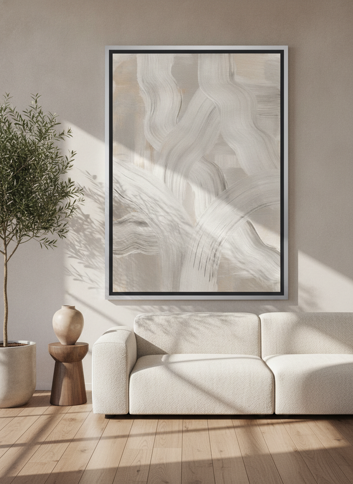 Oversized statement canvas wall art with a silver leaf surround styled on the wall in a luxe living room