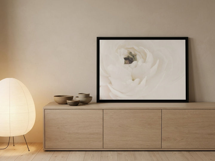 Canvas wall art with a black surround standing on a sideboard in a warm Japandi nursery