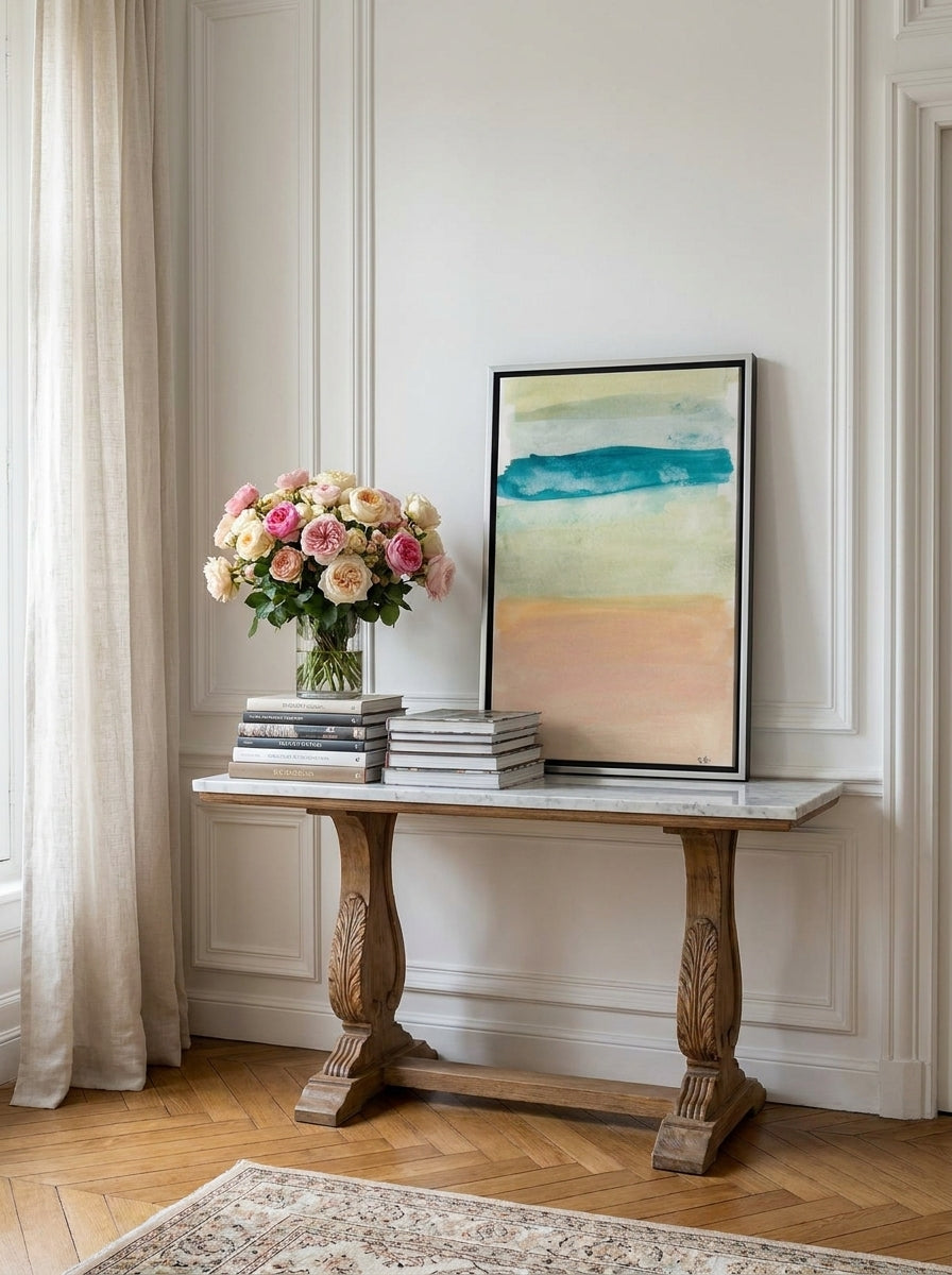 Canvas wall art with a silver leaf surround standing on a console in a Parisian bedroom