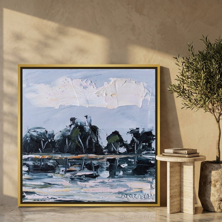 Canvas wall art with a gold leaf surround leaning against the wall in a luxe bedroom