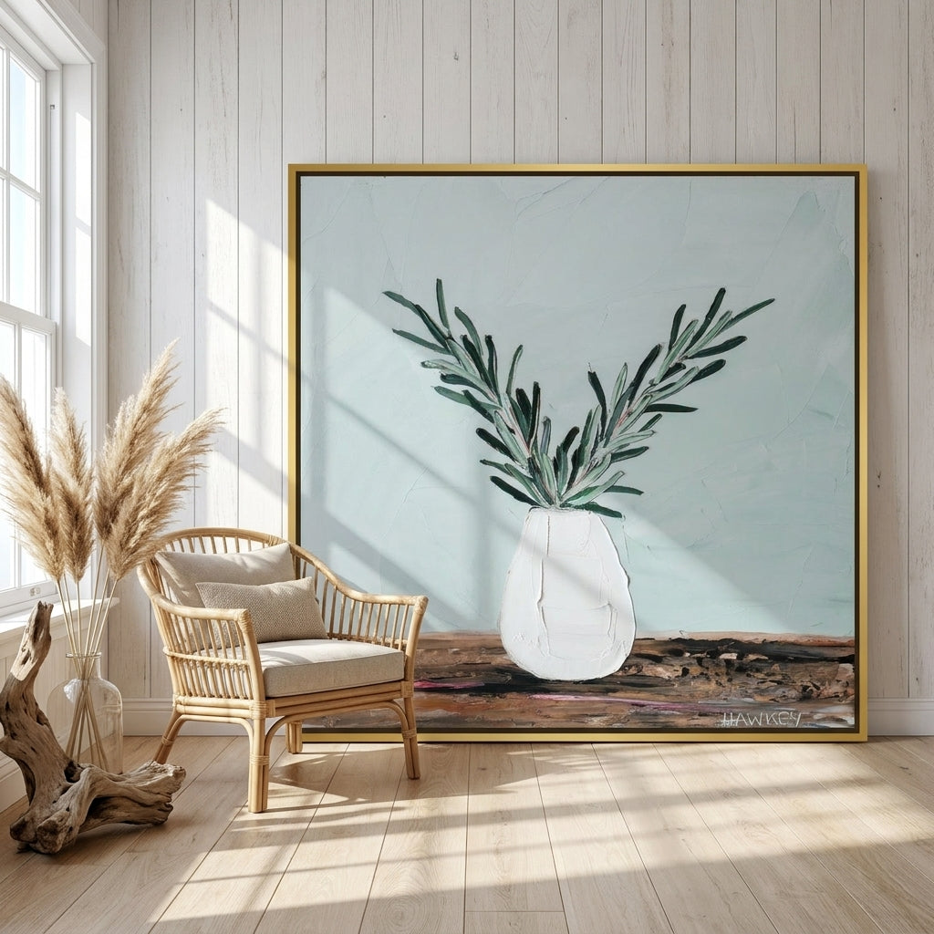 Oversized statement canvas wall art with a gold leaf surround leaning against the wall in a coastal bedroom