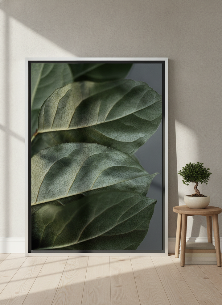 Oversized statement canvas wall art with a silver leaf surround leaning against the wall in a warm Japandi dining room
