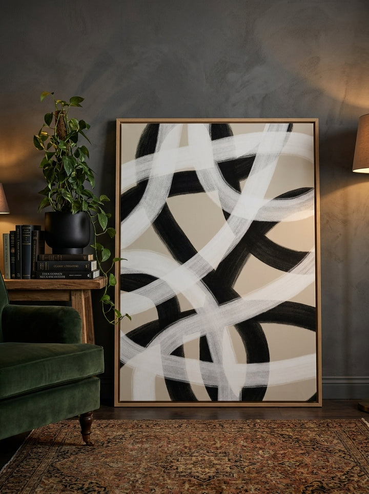 Oversized statement canvas wall art with a natural timber surround leaning against the wall in a moody dining room