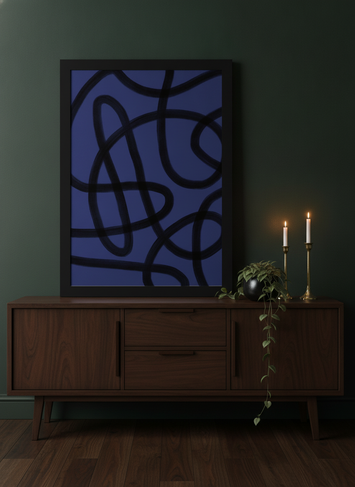 Modern wall art print standing on a sideboard in a moody home office