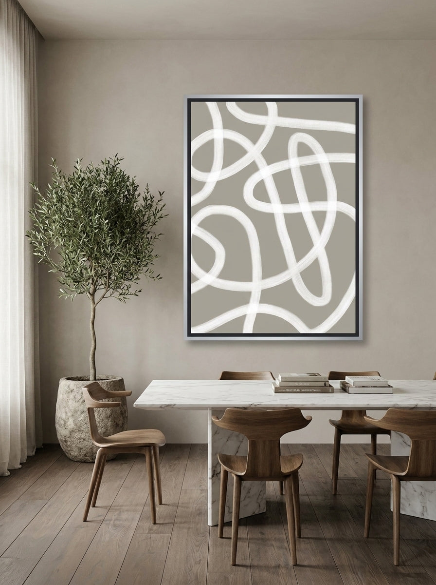 Oversized statement canvas wall art with a silver leaf surround styled on the wall in a luxe dining room
