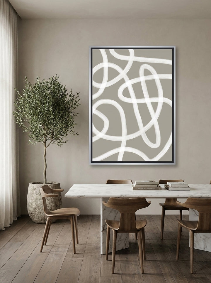 Oversized statement canvas wall art with a silver leaf surround styled on the wall in a luxe dining room