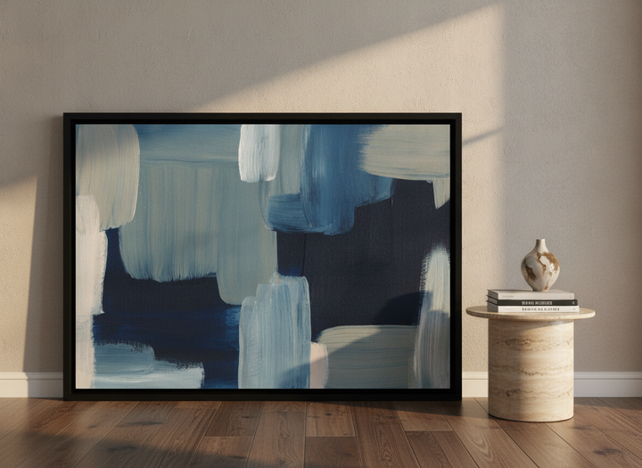Oversized statement canvas wall art with a black surround leaning against the wall in a luxe living room