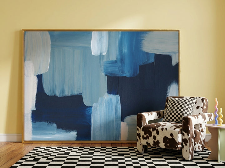 Oversized statement canvas wall art with a gold leaf surround leaning against the wall in a colourful eclectic living room