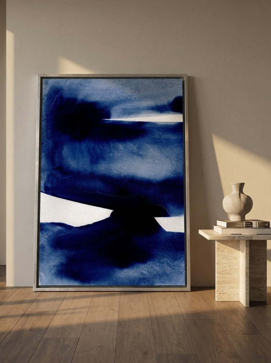 Oversized statement canvas wall art with a silver leaf surround leaning against the wall in a luxe living room
