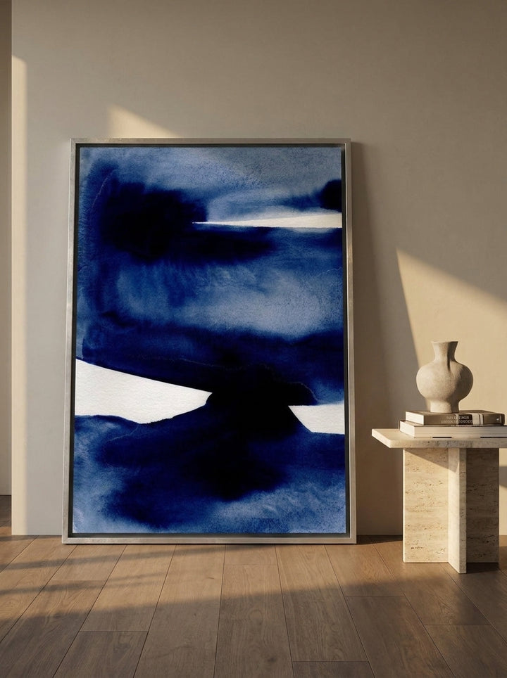 Oversized statement canvas wall art with a silver leaf surround leaning against the wall in a luxe living room