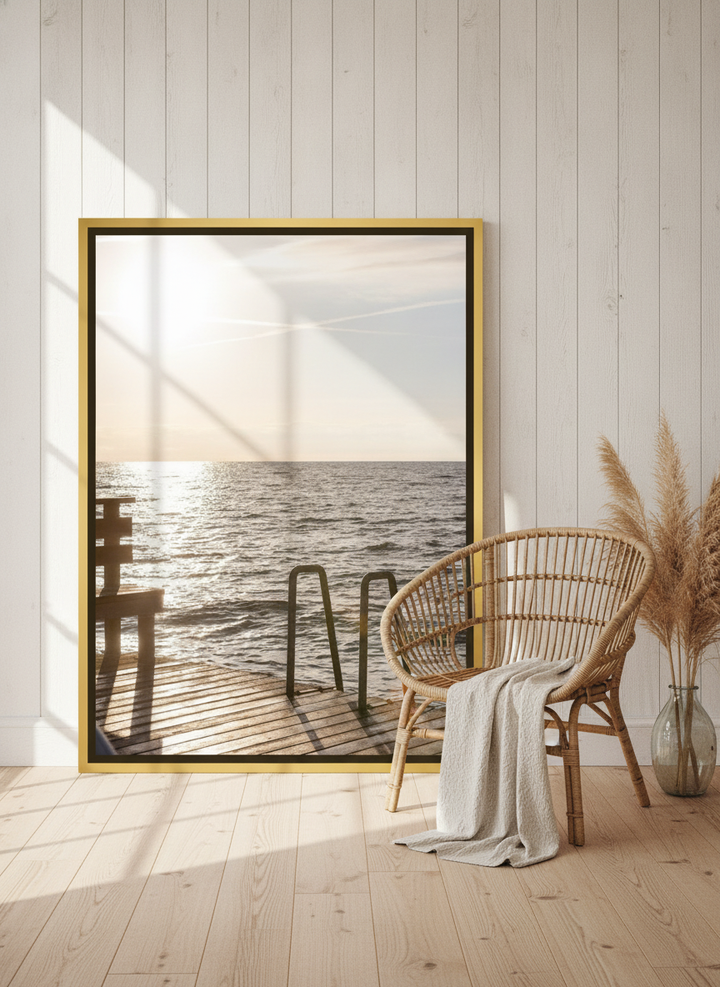 Oversized statement canvas wall art with a gold leaf surround leaning against the wall in a coastal bedroom