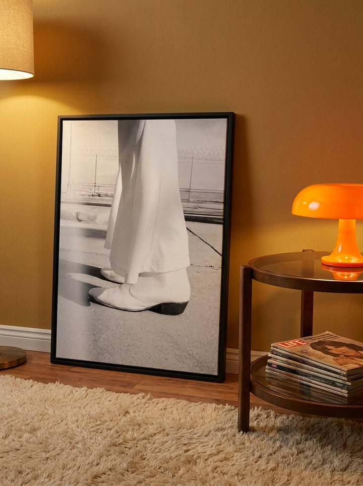 Oversized statement canvas wall art with a black surround leaning against the wall in a retro 70s living room