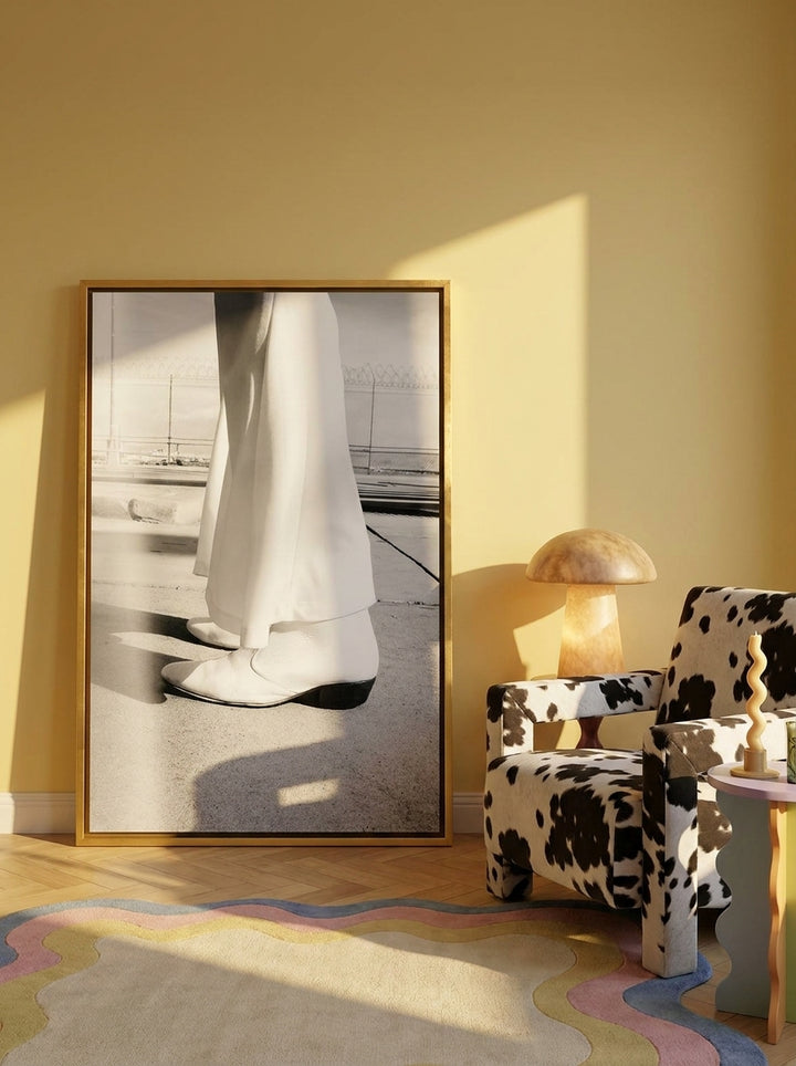 Oversized statement canvas wall art with a gold leaf surround leaning against the wall in a colourful eclectic living room