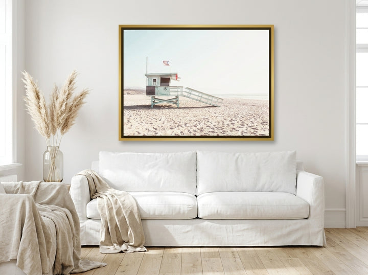 Oversized statement canvas wall art with a gold leaf surround styled on the wall in a coastal living room