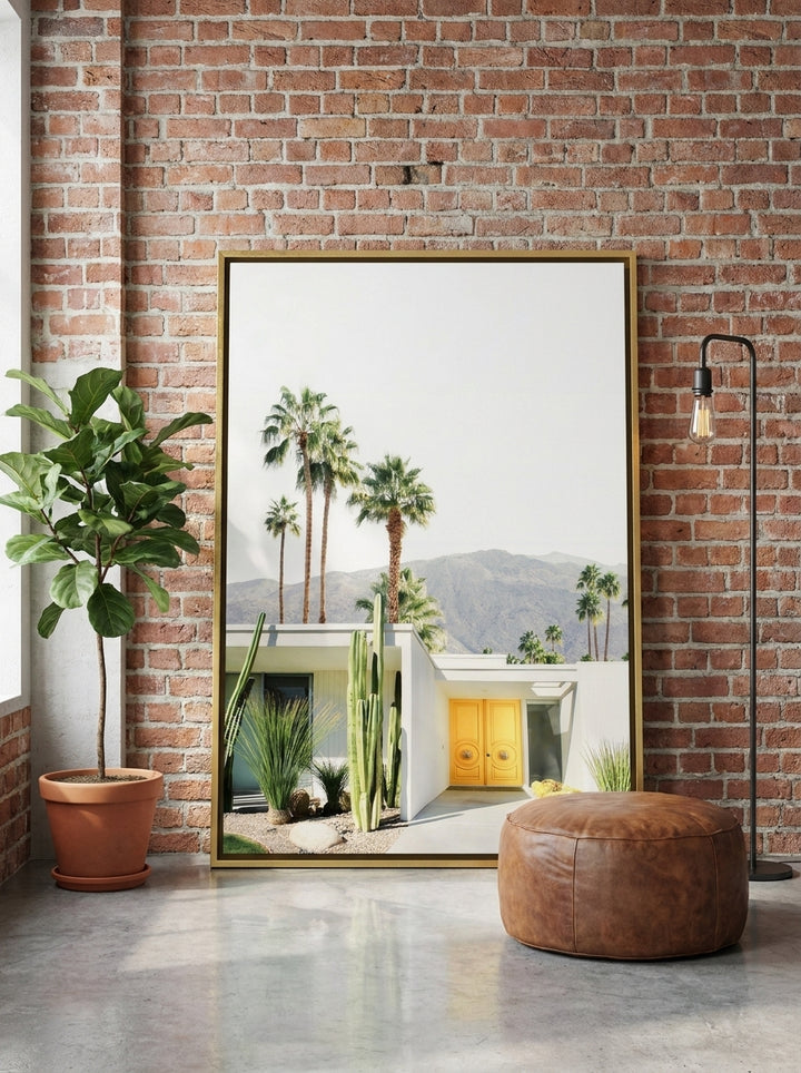 Oversized statement canvas wall art with a gold leaf surround leaning against the wall in an industrial loft living room
