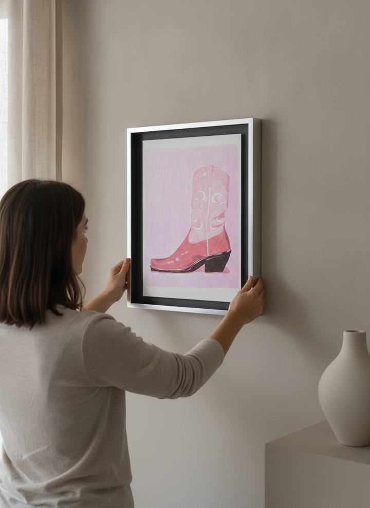 Person holding canvas wall art with a silver leaf surround in a luxe living room
