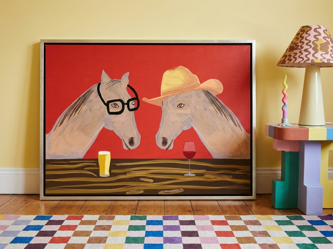Canvas wall art with a silver leaf surround leaning against the wall in a colourful eclectic living room