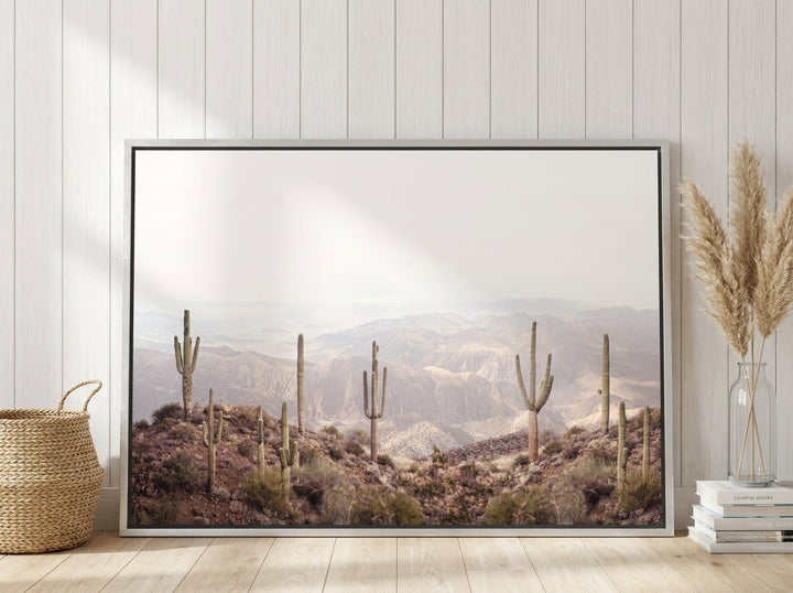 Oversized statement canvas wall art with a silver leaf surround leaning against the wall in a coastal dining room