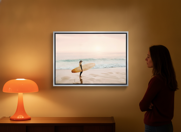 Person holding canvas wall art with a silver leaf surround in a retro 70s living room
