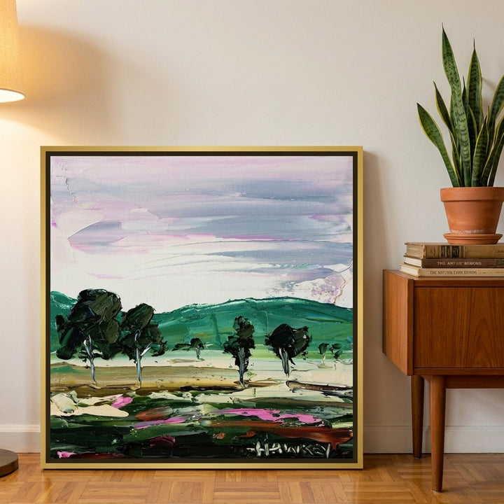 Canvas wall art with a gold leaf surround leaning against the wall in a mid-century living room