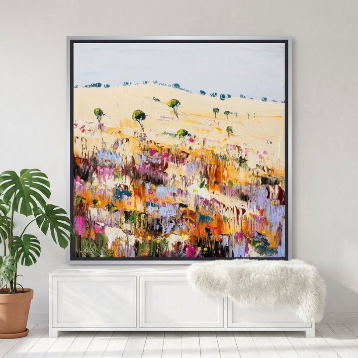 Canvas wall art with a silver leaf surround standing on a sideboard in a bright Scandinavian dining room