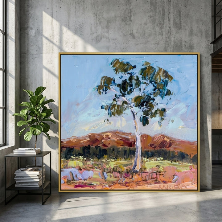 Oversized statement canvas wall art with a gold leaf surround leaning against the wall in an industrial loft living room