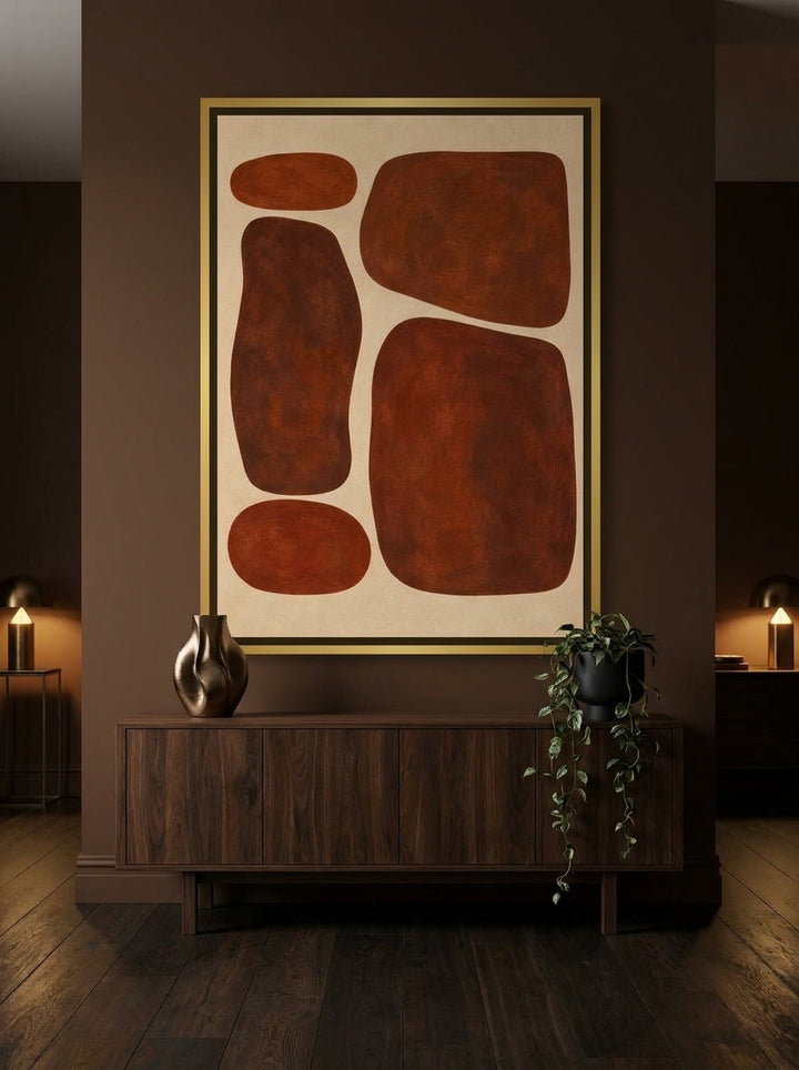 Oversized statement canvas wall art with a gold leaf surround styled on the wall in a moody living room